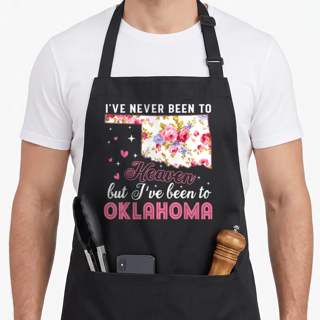 Heaven oklahoma boy apron - Floral Oklahoma state map with stacked text and scattered pink hearts and stars — shown on a black cotton canvas apron against a white background
