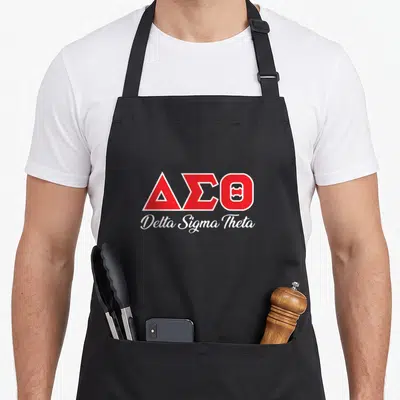 Theta paraphernalia sorority apron - Red Delta Sigma Theta Greek letters and white script on black bib — shown on a black cotton canvas apron against a white background