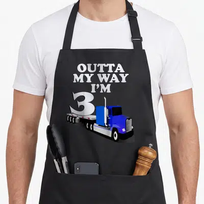 Funny birthday semi truck apron - Blue semi-truck carrying large number 3 with stacked text OUTTA MY WAY I M — shown on a black cotton canvas apron against a white background