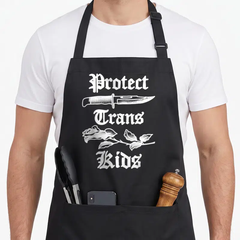Protect rose apron - White gothic text Protect Trans Kids with knife and rose line art — shown on a black cotton canvas apron against a white background