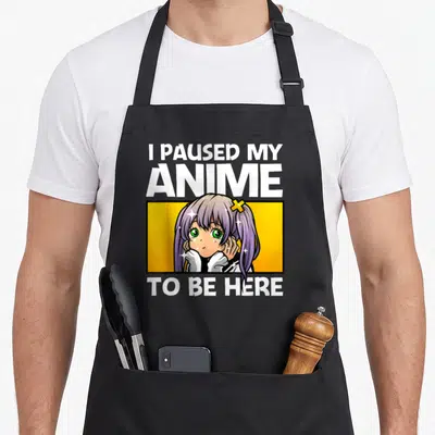 Cool anime apron - Purple anime girl in yellow box with text I paused my anime to be here — shown on a black cotton canvas apron against a white background