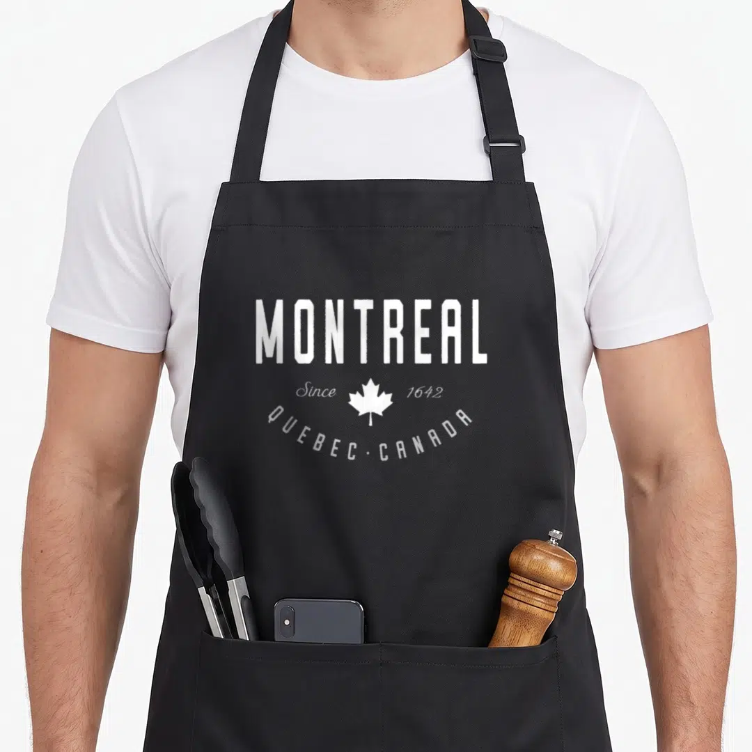 Montreal canada aprons - White MONTREAL text above a maple leaf flanked by Since 1642 and arched QUEBEC CANADA below — shown on a black cotton canvas apron against a white background