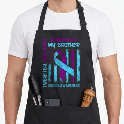 Brother ribbon apron - Teal and purple ribbon over distressed flag with memory text — shown on a black cotton canvas apron against a white background