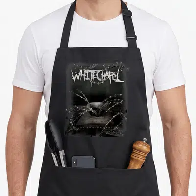 Chapel band apron - Black white grey barbed wire over wooden plank with Whitechapel The Somatic Defilement text — shown on a black cotton canvas apron against a white background