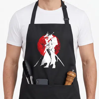 Japanese japan apron - White samurai silhouette holding two katanas in front of a textured red circle — shown on a black cotton canvas apron against a white background