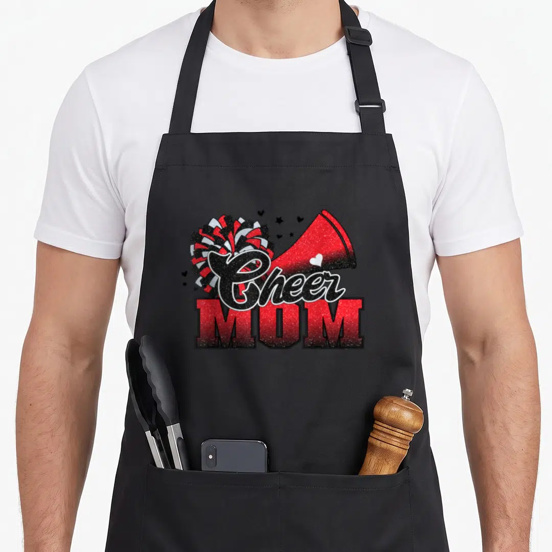Football leopard print cooking apron - Cheer MOM text with red pom-pom and megaphone in retro style — shown on a black cotton canvas apron against a white background