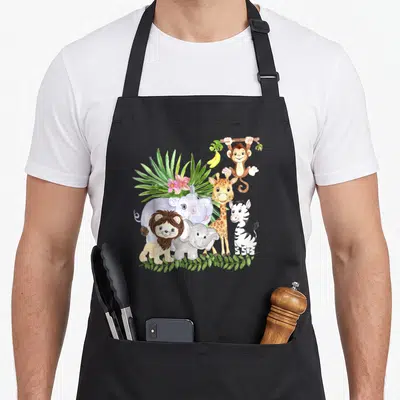 Animal wildlife birthday apron - Watercolor jungle animals including lion, elephant, giraffe, zebra, and monkey — shown on a black cotton canvas apron against a white background
