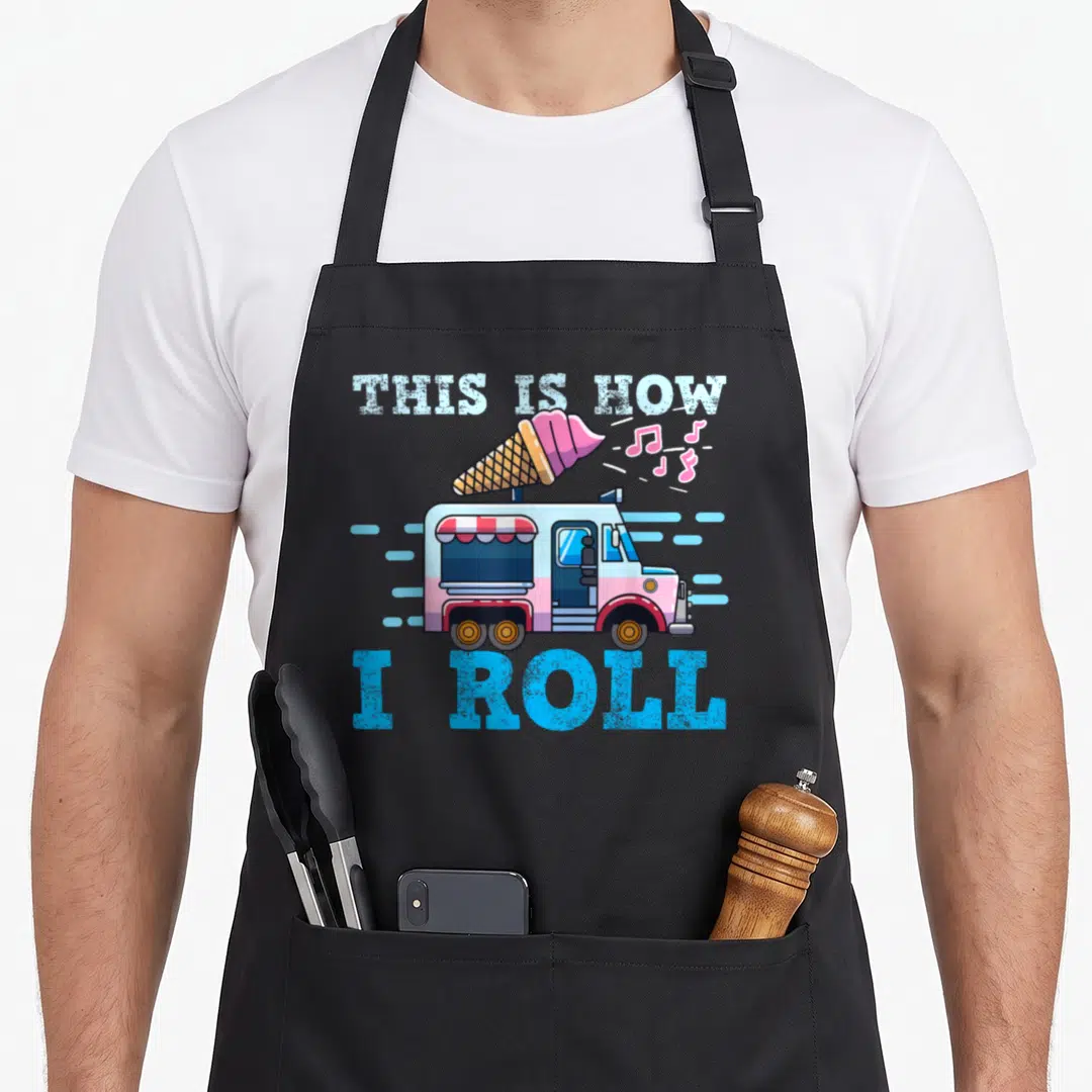 Truck ice cream apron - Cartoon ice cream truck with giant cone and text THIS IS HOW I ROLL in blue pink white and tan — shown on a black cotton canvas apron against a white background