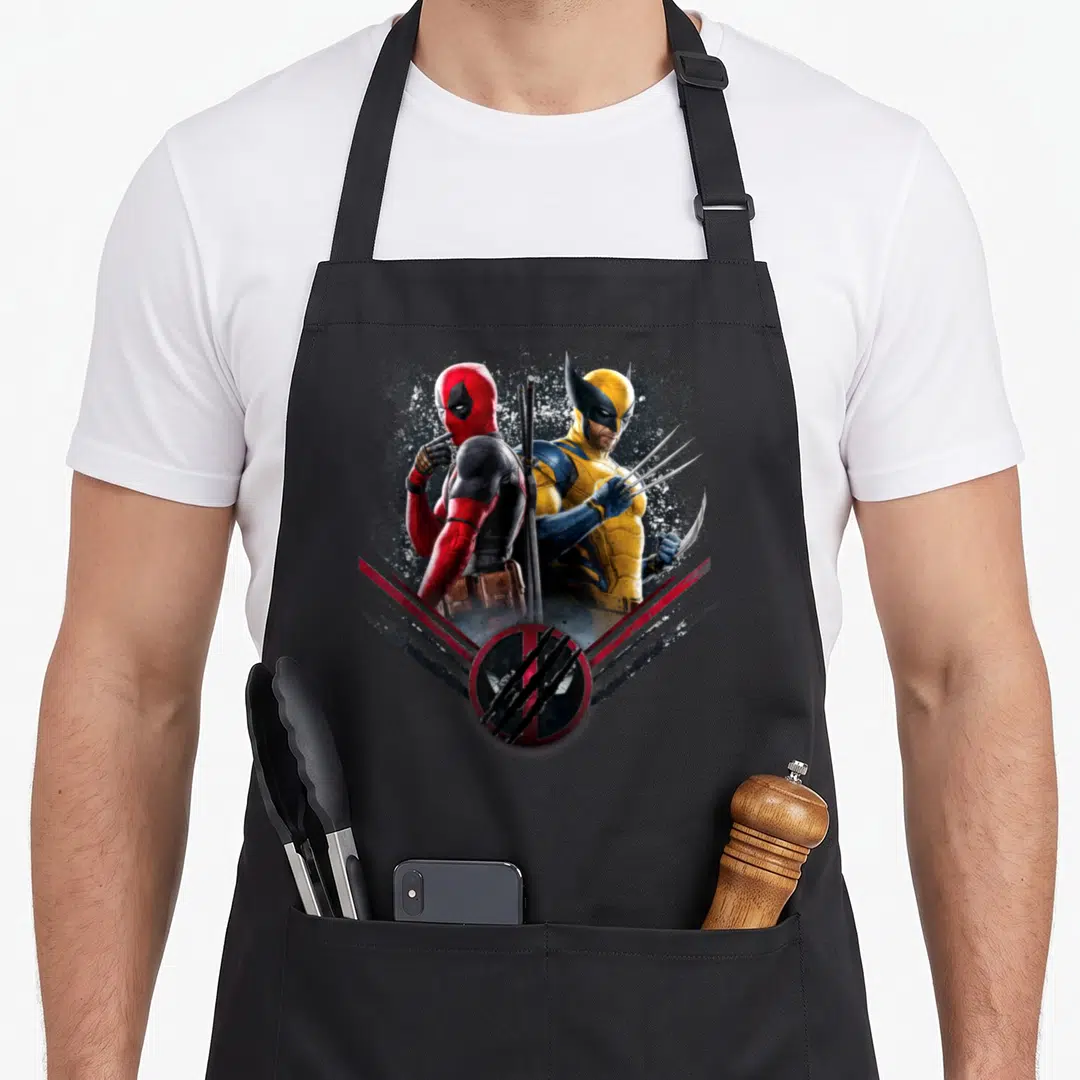 Studio by apron - Deadpool and Wolverine back-to-back photo print with circular claw mark logo in red and blue — shown on a black cotton canvas apron against a white background