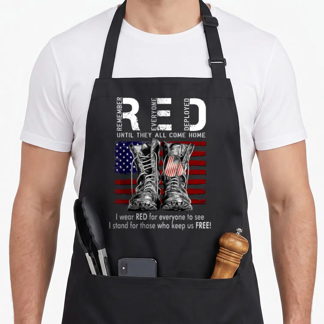 Military black friday apron - Combat boots dog tags and deployed text over distressed US flag — shown on a black cotton canvas apron against a white background