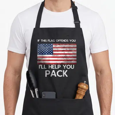 Offend flag back apron - Distressed USA flag in red white blue between text reading IF THIS FLAG OFFENDS YOU I'LL HELP — shown on a black cotton canvas apron against a white background