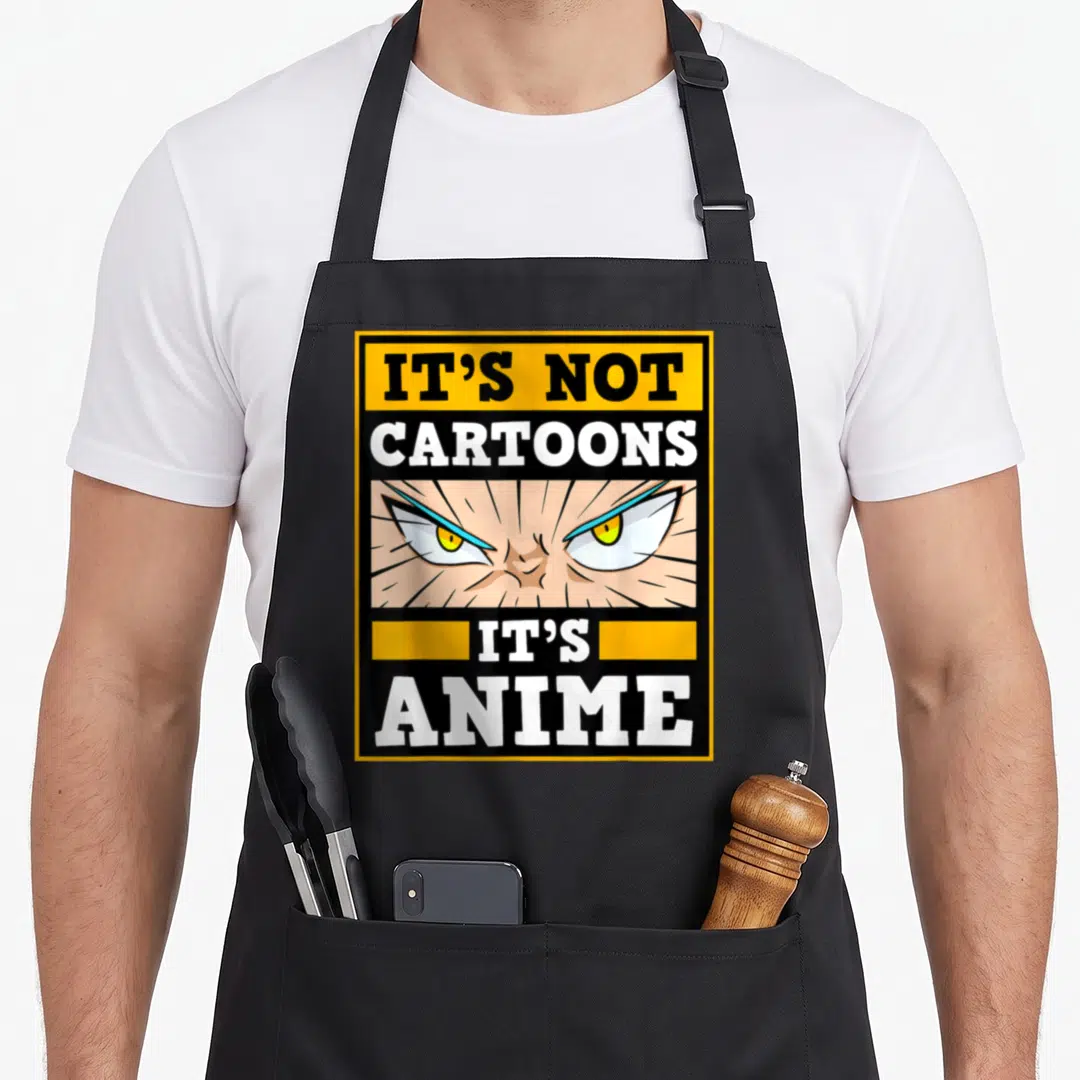 Anime cartoon apron - Angry anime eyes with It's Not Cartoons It's Anime text in yellow black frame — shown on a black cotton canvas apron against a white background