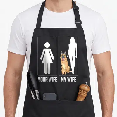 Shepherd personalized dog apron - YOUR WIFE MY WIFE text below restroom sign and seated German Shepherd illustration — shown on a black cotton canvas apron against a white background