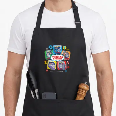 Grid best friend aprons - Five cartoon trains in colored squares around central Thomas and Friends logo with track — shown on a black cotton canvas apron against a white background