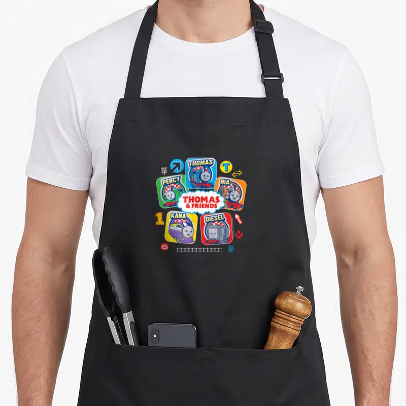 Grid best friend aprons - Five cartoon trains in colored squares around central Thomas and Friends logo with track — shown on a black cotton canvas apron against a white background
