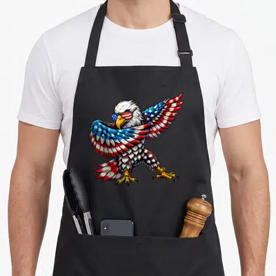 Eagle patriotic 4th of july apron - Bald eagle wearing sunglasses with red white and blue flag pattern wings — shown on a black cotton canvas apron against a white background