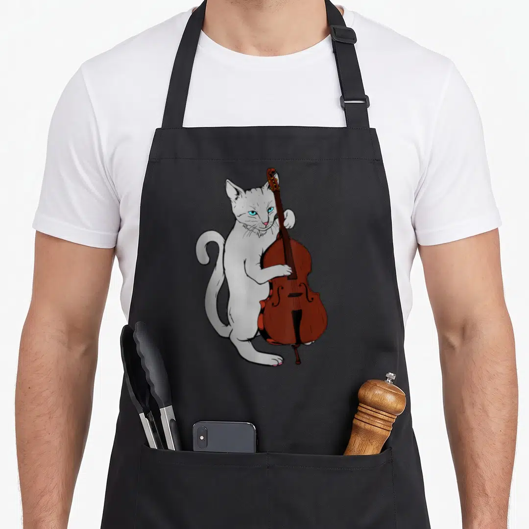 Jazz cat apron - Light grey cat standing holding brown cello cartoon illustration — shown on a black cotton canvas apron against a white background