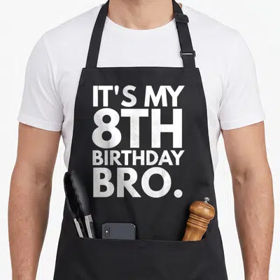 Eighth birthday apron - White stacked text reading IT'S MY 8TH BIRTHDAY BRO on dark background — shown on a black cotton canvas apron against a white background