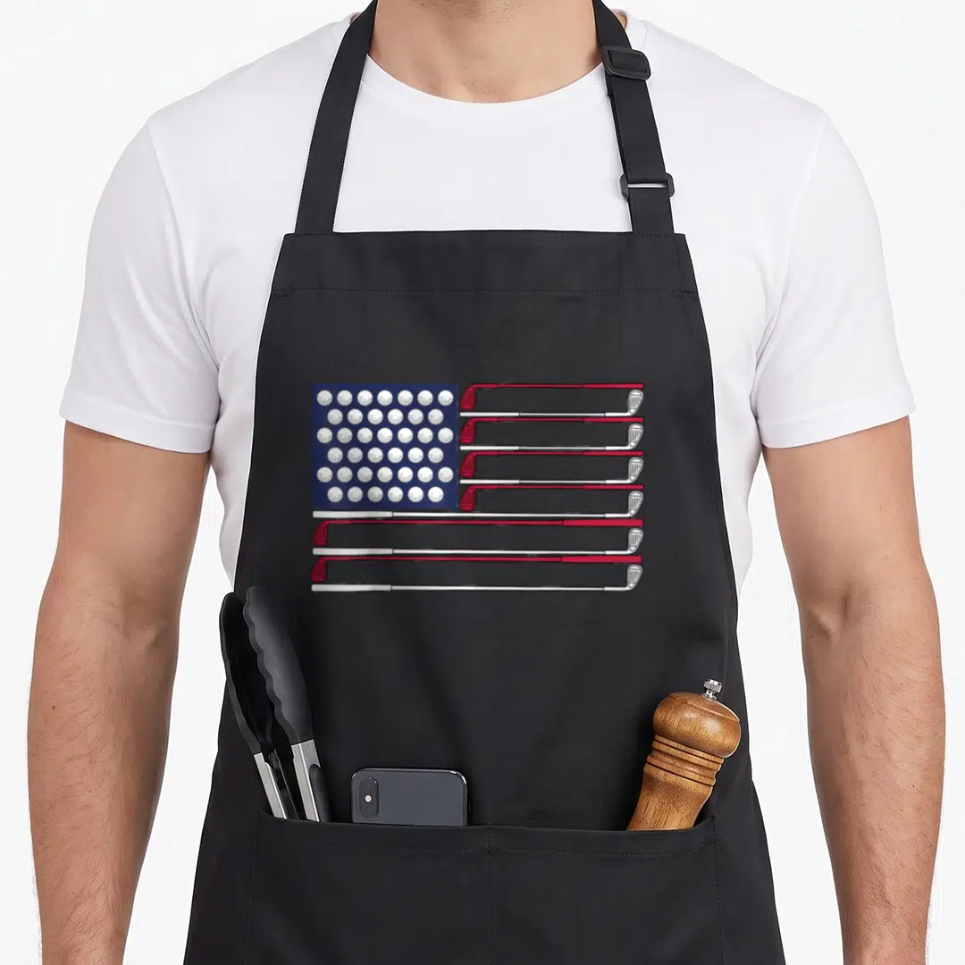 Golf 4th of july apron - American flag made of white golf balls and red white clubs on blue background — shown on a black cotton canvas apron against a white background