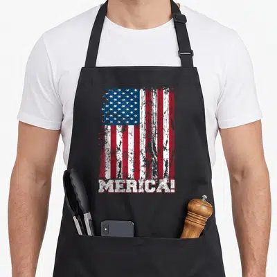Independence 4th of july apron - Distressed USA flag with MERICA! text below in red white blue on black apron — shown on a black cotton canvas apron against a white background