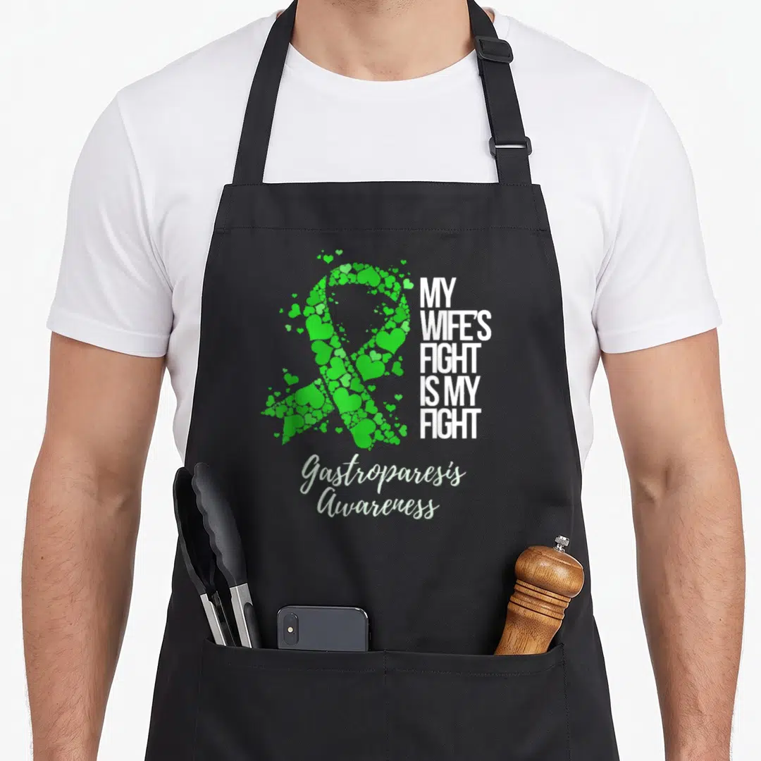 Gastroparesis wife apron - Green scattered hearts forming a ribbon next to white block text and script lettering — shown on a black cotton canvas apron against a white background