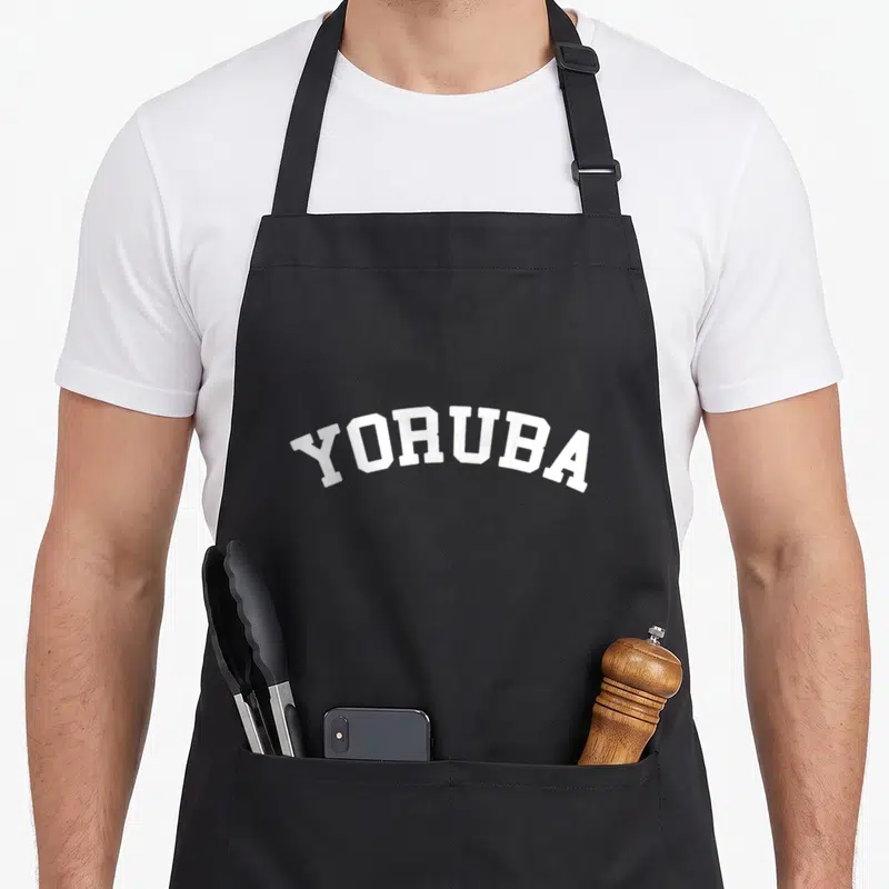 Yoruba collegiate aprons - White YORUBA text in an arched collegiate font style — shown on a black cotton canvas apron against a white background