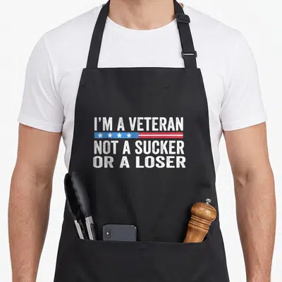 Sucker apron or apron - Distressed white text I'M A VETERAN NOT A SUCKER OR A LOSER with star stripe — shown on a black cotton canvas apron against a white background