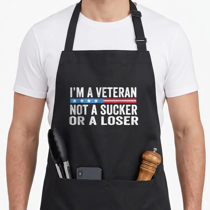 Sucker apron or apron - Distressed white text I'M A VETERAN NOT A SUCKER OR A LOSER with star stripe — shown on a black cotton canvas apron against a white background