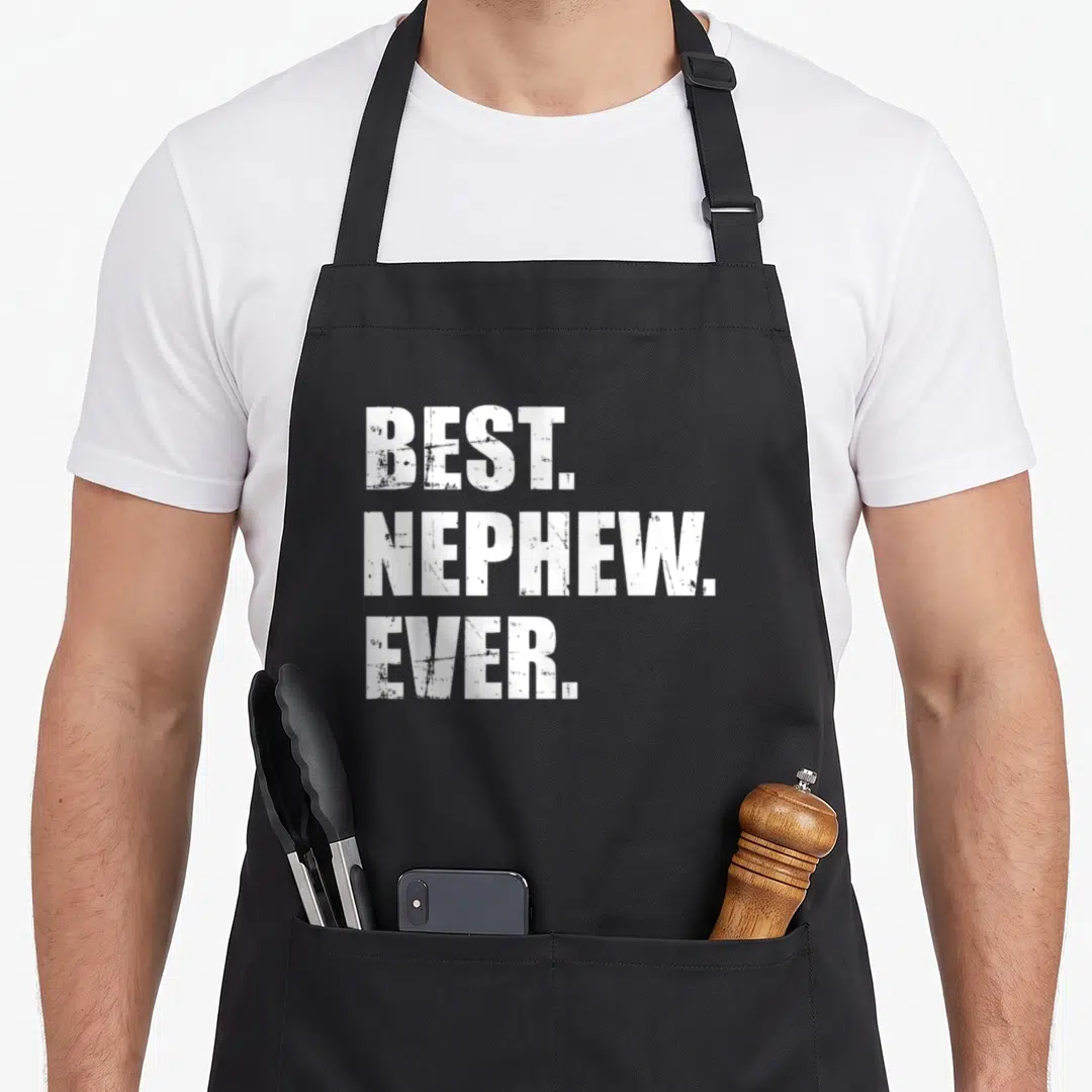 Funny nephew apron - White distressed text reading BEST. NEPHEW. EVER. stacked vertically on a dark background — shown on a black cotton canvas apron against a white background