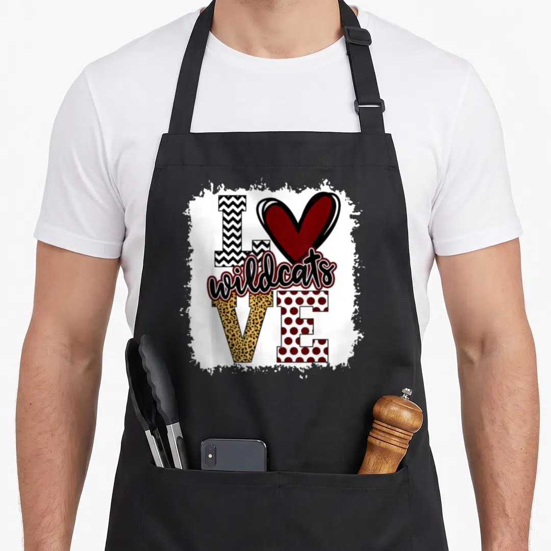 Mascot cat apron - I Love Wildcats text art with chevron, leopard, polka dot letters and maroon heart on distressed — shown on a black cotton canvas apron against a white background