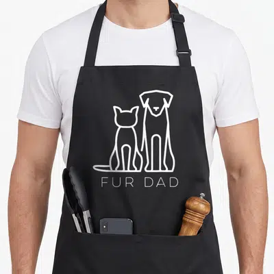 Fur personalized dog apron - White line art of cat and dog sitting side by side with FUR DAD text below — shown on a black cotton canvas apron against a white background