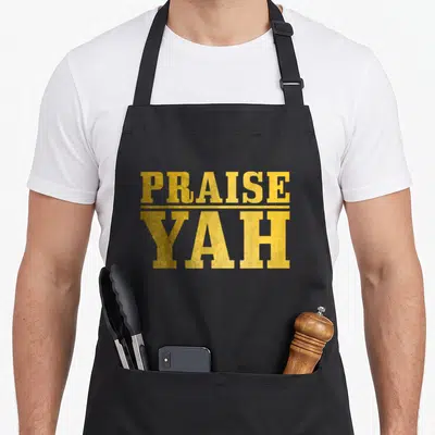 Praise jewish apron - Gold PRAISE YAH stacked typography separated by thin horizontal line on black background — shown on a black cotton canvas apron against a white background
