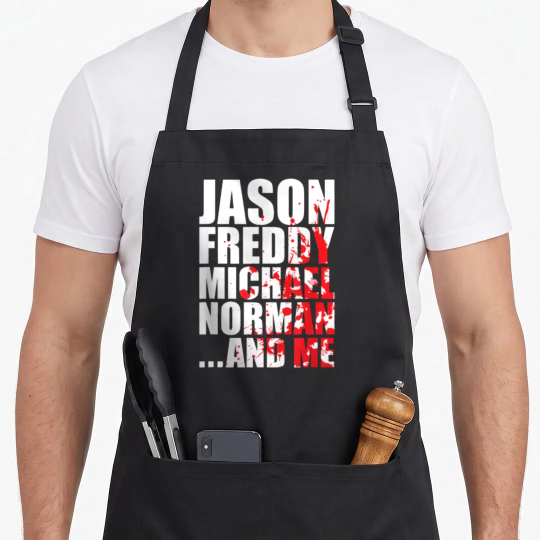 Famous bloody apron - White text listing Jason Freddy Michael Norman And Me with red blood splatters — shown on a black cotton canvas apron against a white background