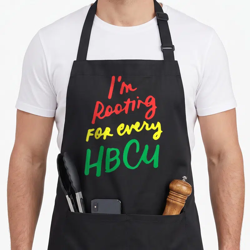 Hbcu university apron - Stacked red yellow green text reading I'm Rooting For Every HBCU — shown on a black cotton canvas apron against a white background