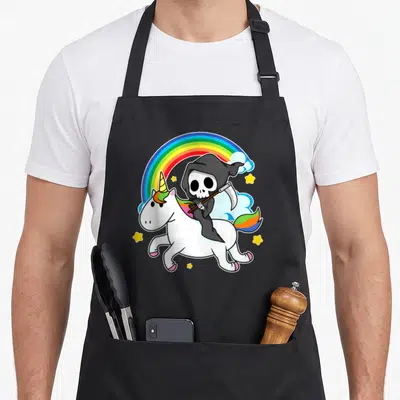 Reaper halloween apron - Cartoon grim reaper riding white unicorn under rainbow with yellow stars and clouds — shown on a black cotton canvas apron against a white background