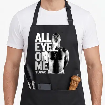 Eyez tupac apron - All Eyez On Me text stacked next to shirtless man photo on grey background — shown on a black cotton canvas apron against a white background