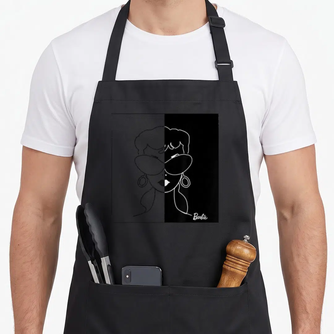 Mono 60th birthday apron - Minimalist line art woman face with sunglasses on split grey and black background — shown on a black cotton canvas apron against a white background