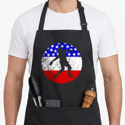 Discus american flag apron - Grey discus thrower silhouette over distressed blue star and red white stripe circle — shown on a black cotton canvas apron against a white background