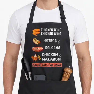 Wing chicken apron - Cartoon chicken wing, hotdog, bologna, and chicken with macaroni next to white lyrics — shown on a black cotton canvas apron against a white background
