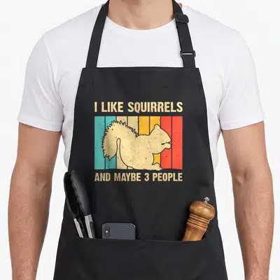 Funny squirrel pet apron - Beige squirrel silhouette over five vertical colored stripes with sarcastic text about — shown on a black cotton canvas apron against a white background