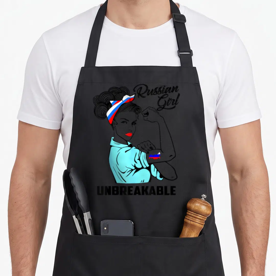 Unbreakable russian apron - Cartoon woman flexing arm with Russian flag tattoo and headband — shown on a black cotton canvas apron against a white background