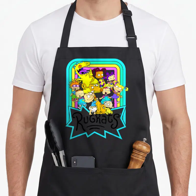 Neon rainbow apron - Rugrats characters in rainbow frame with blue jagged logo bubble — shown on a black cotton canvas apron against a white background