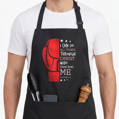 Boxing christian apron - Red distressed boxing glove next to stacked white and pink Philippians 4:13 lettering — shown on a black cotton canvas apron against a white background
