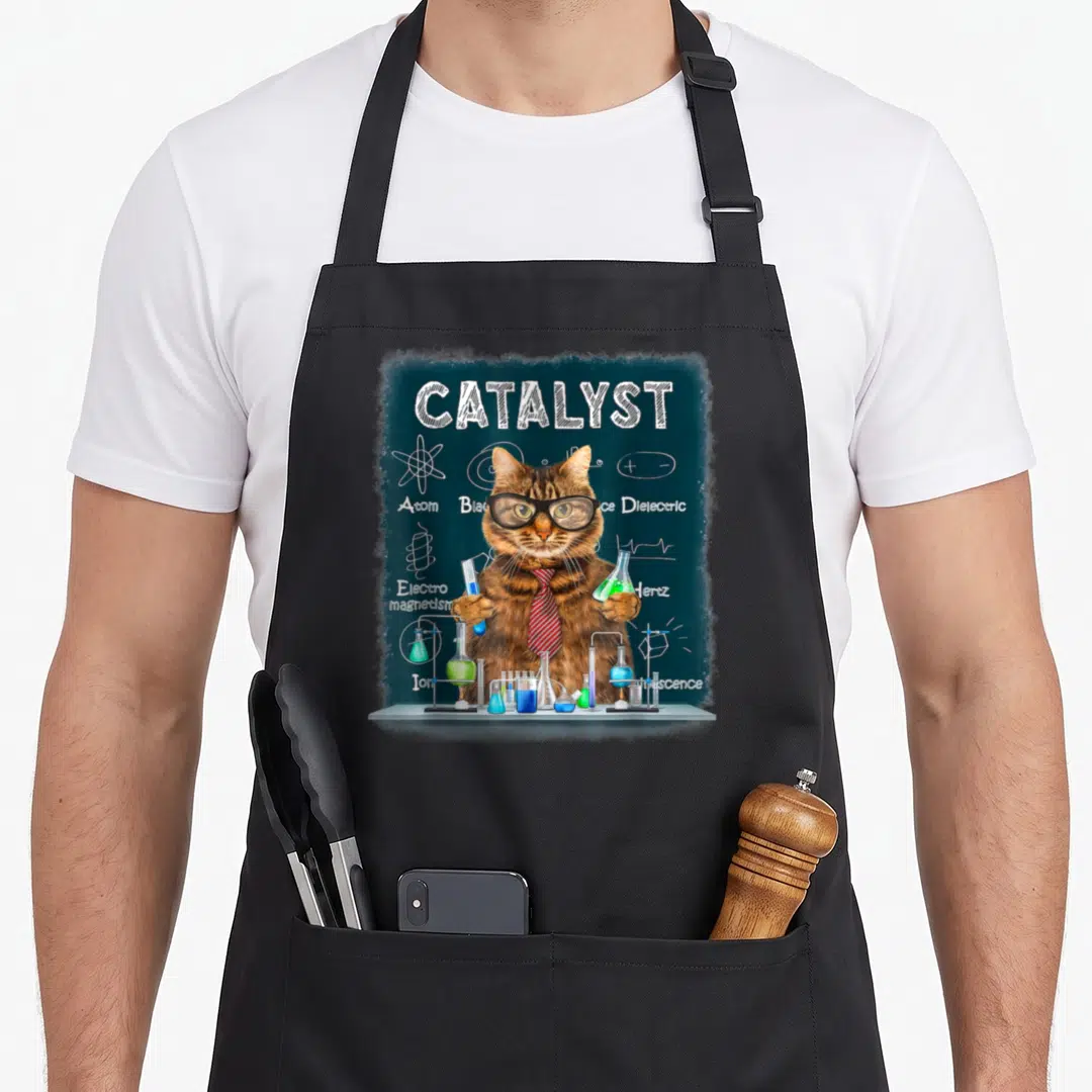 Catalyst cat apron - Realistic brown cat with glasses and tie holding lab flasks in front of teal chalkboard — shown on a black cotton canvas apron against a white background