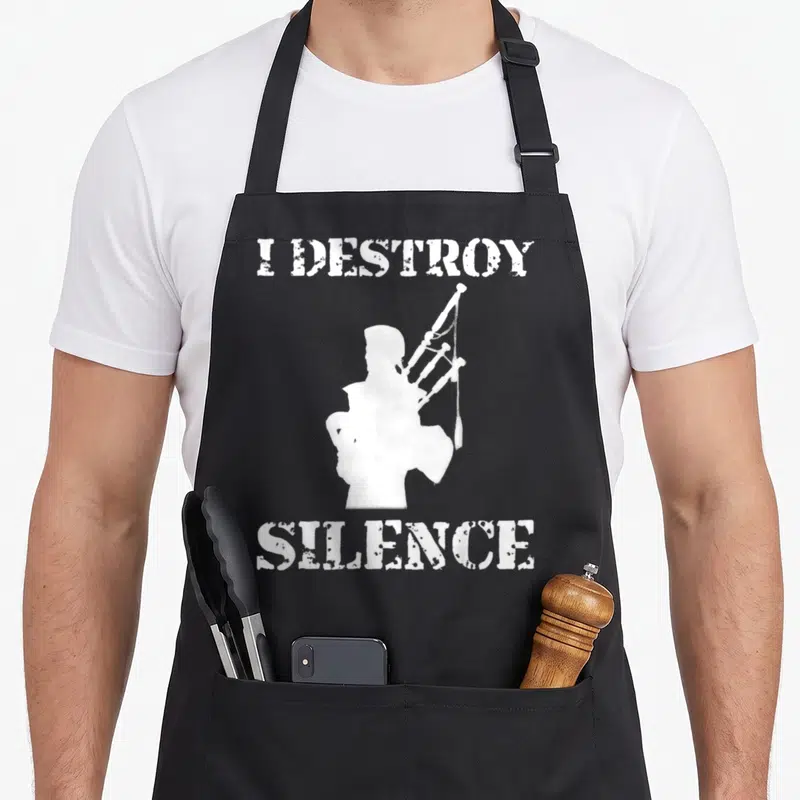 Destroy bagpipes apron - White bagpiper silhouette flanked by I DESTROY SILENCE text — shown on a black cotton canvas apron against a white background