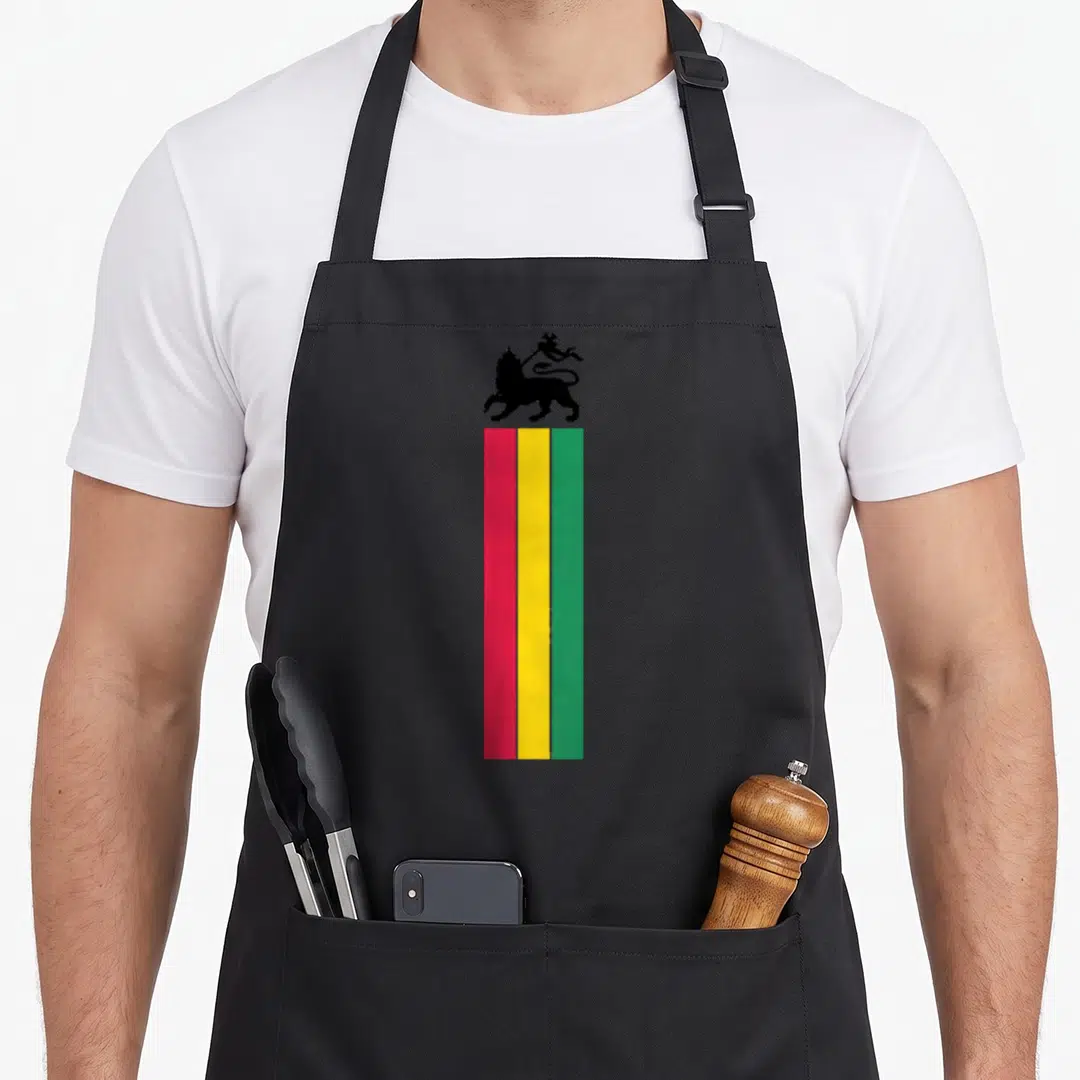 Juda lion apron - Black lion silhouette above three vertical stripes of red, yellow, and green — shown on a black cotton canvas apron against a white background