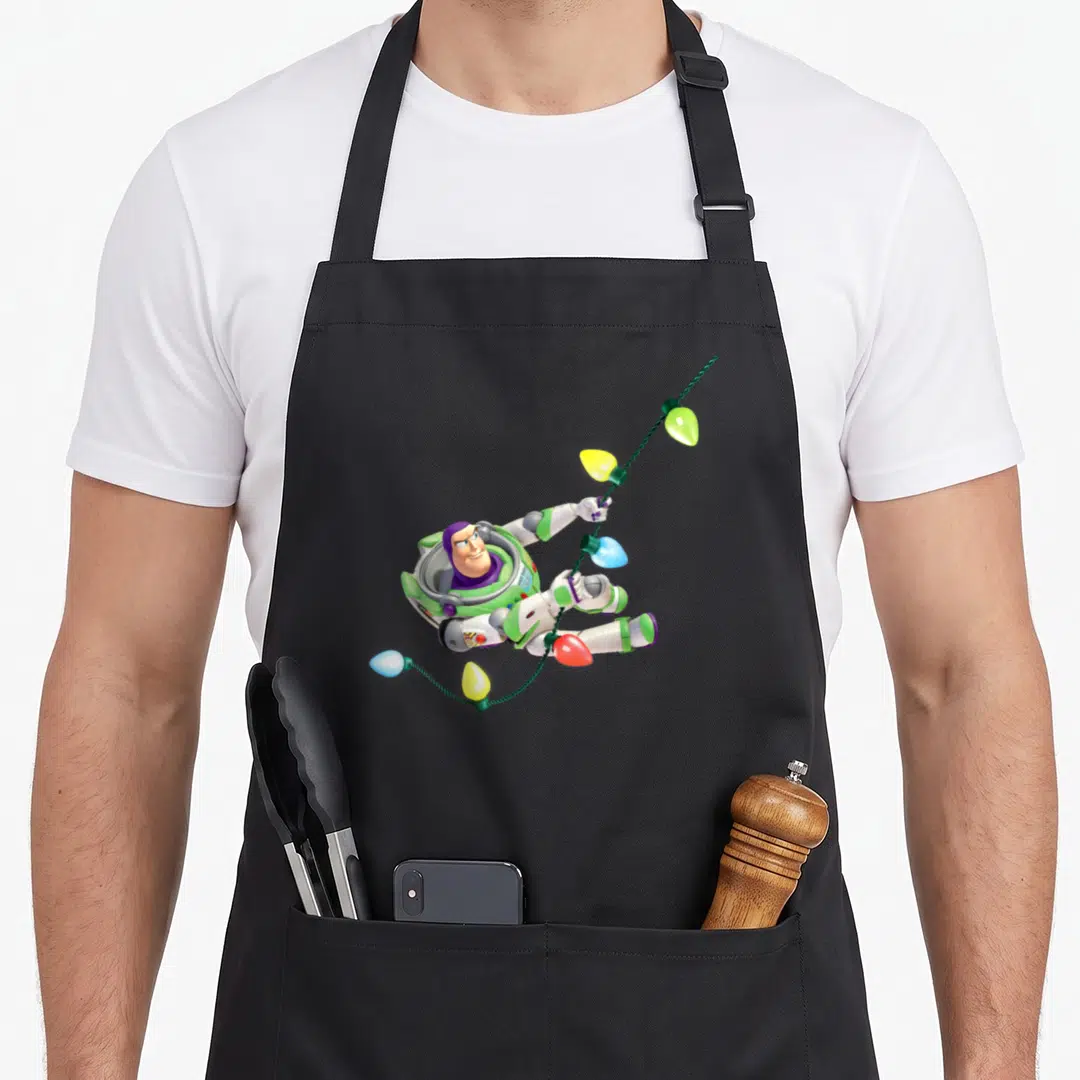 Retro christmas lights apron - Cartoon Buzz Lightyear tangled in white green purple yellow blue and red Christmas light — shown on a black cotton canvas apron against a white background