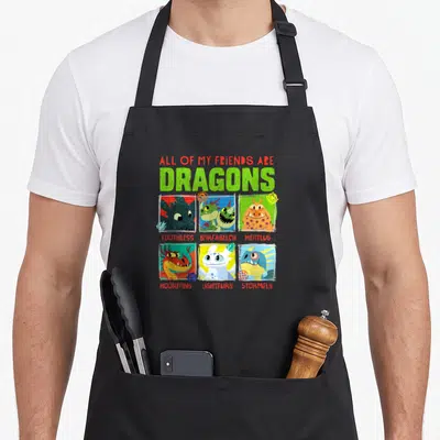 Dragon friends apron - Six dragon heads in colored squares with names Toothless Barf Belch Meatlug Hookfang Lightfury — shown on a black cotton canvas apron against a white background