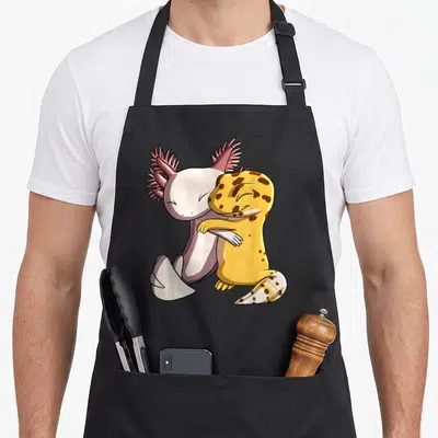 Hugging leopard apron - Cartoon axolotl with pink frills hugging a yellow spotted leopard gecko — shown on a black cotton canvas apron against a white background