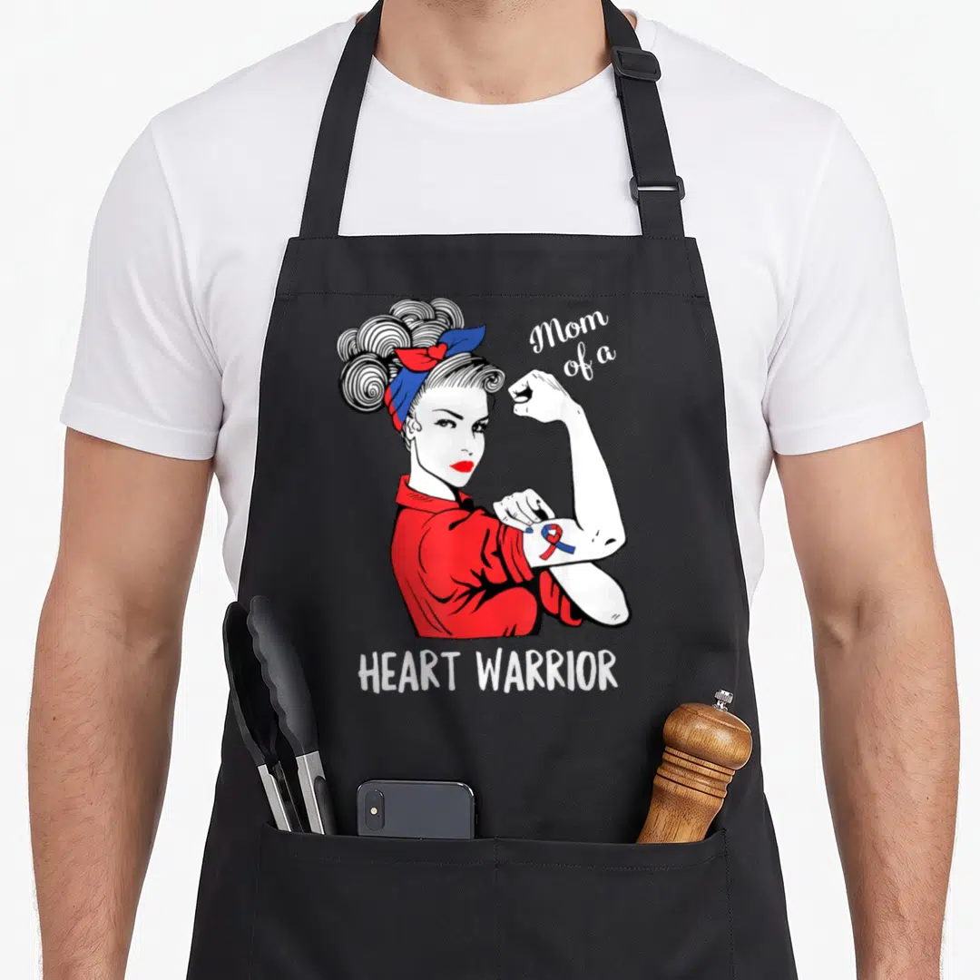 Warrior organ donation apron - Rosie the Riveter flexing arm with red blue ribbon and Mom of a Heart Warrior text — shown on a black cotton canvas apron against a white background